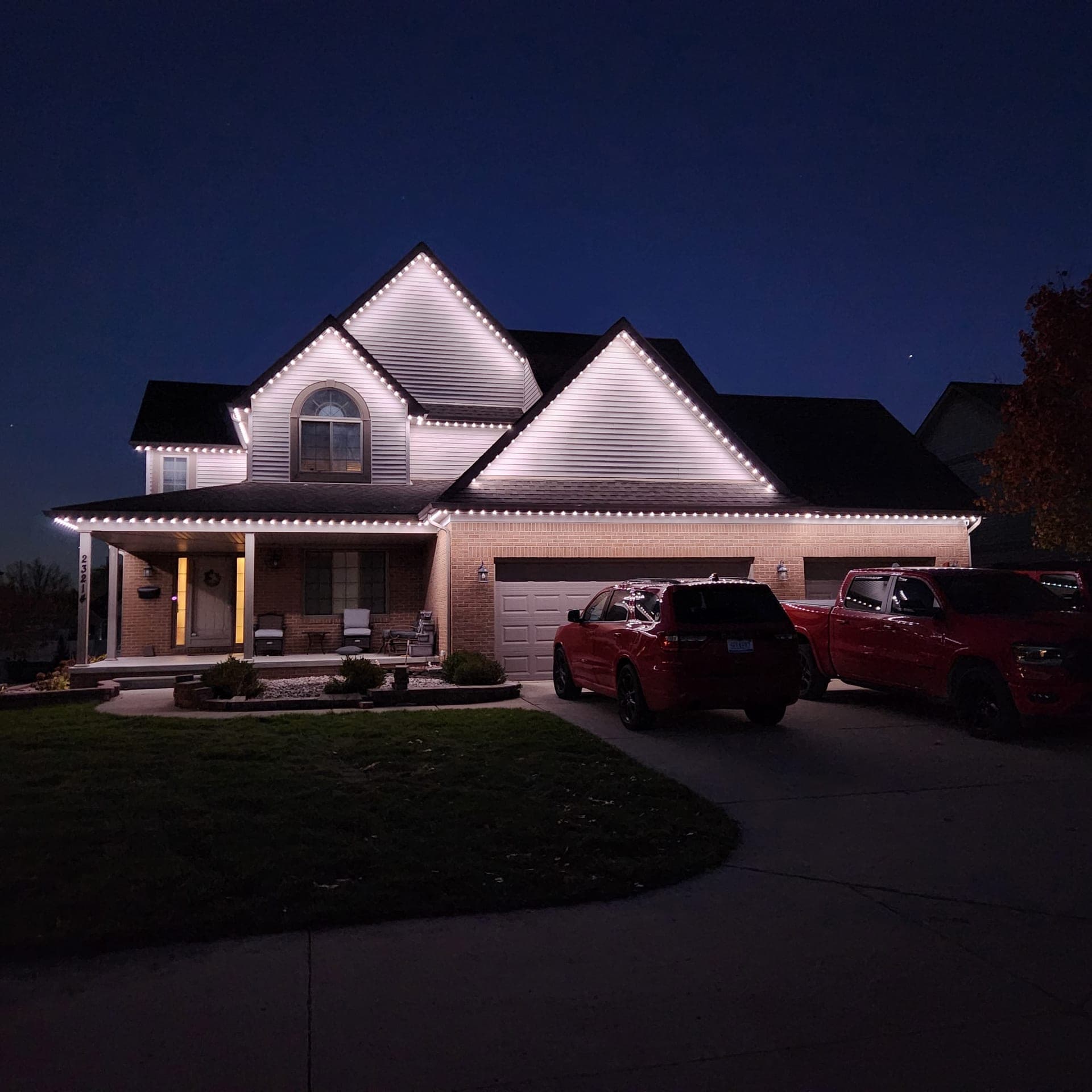 Warm white permanent LED roofline lighting on a two-storey home with a covered front porch and attached garage