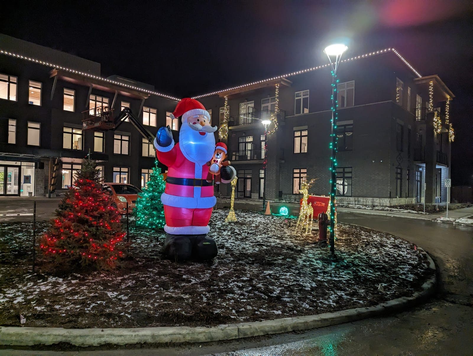 Commercial courtyard holiday display with a giant inflatable Santa, lit reindeer and warm-white roofline lights