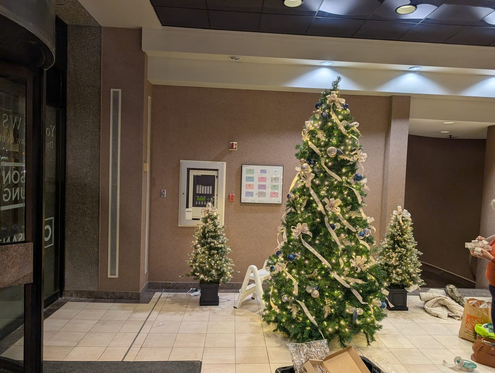 Professionally decorated Christmas tree with blue and gold accents in a commercial lobby.