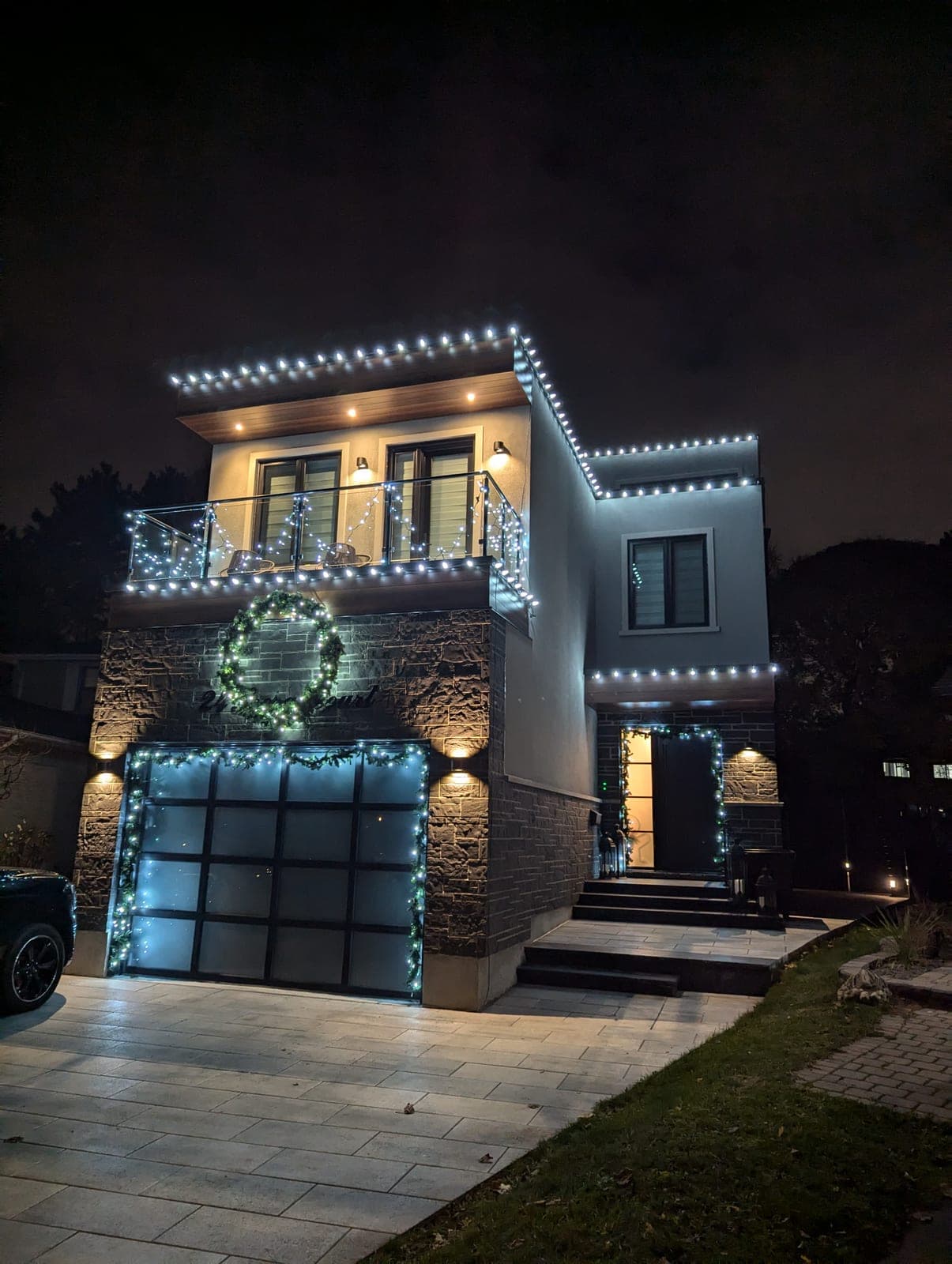 Contemporary home lit with white LED Christmas lights, a glowing wreath and garage garland