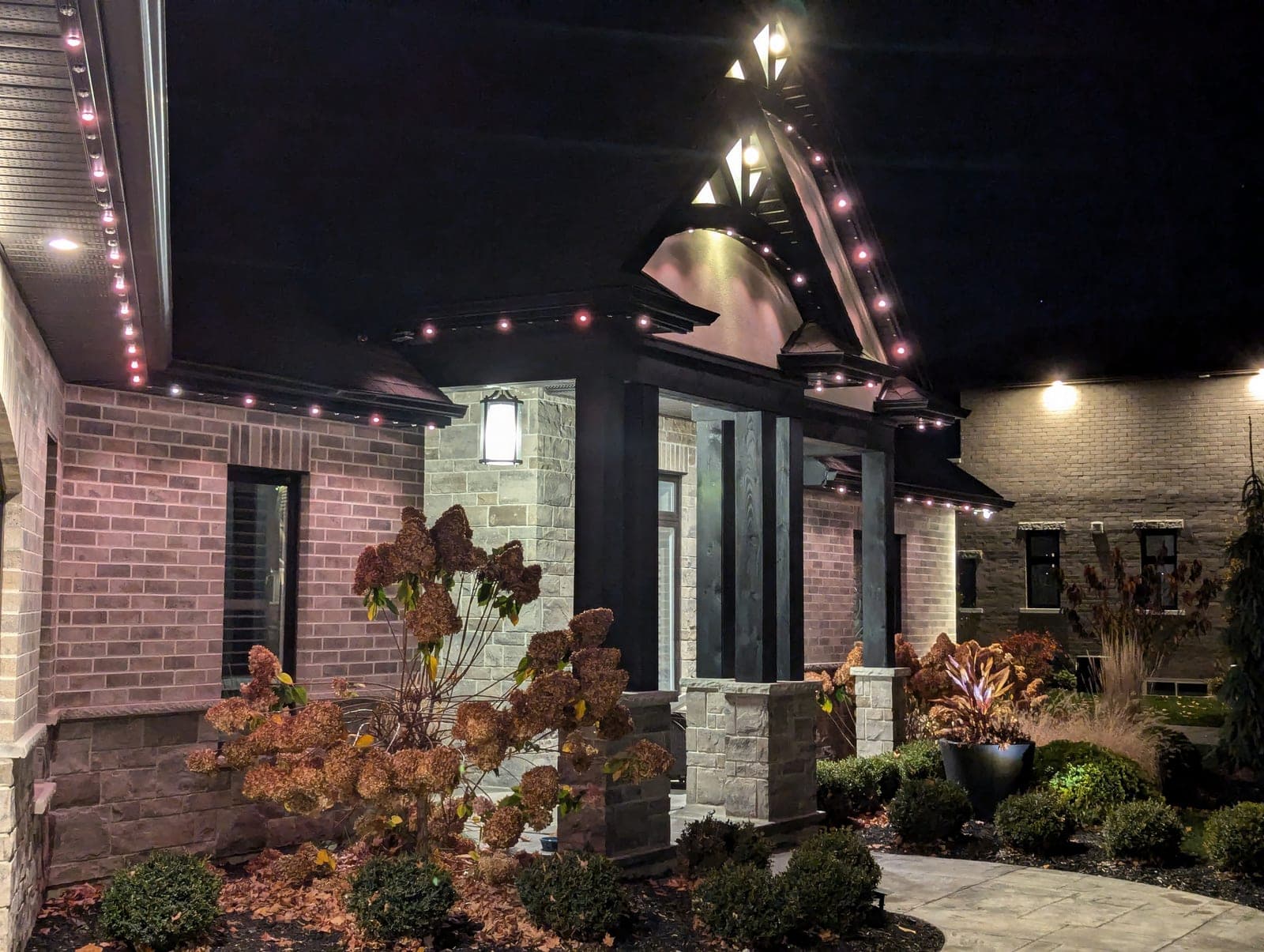 Close-up of a home's eaves and gable peak trimmed with warm C9 Christmas lights