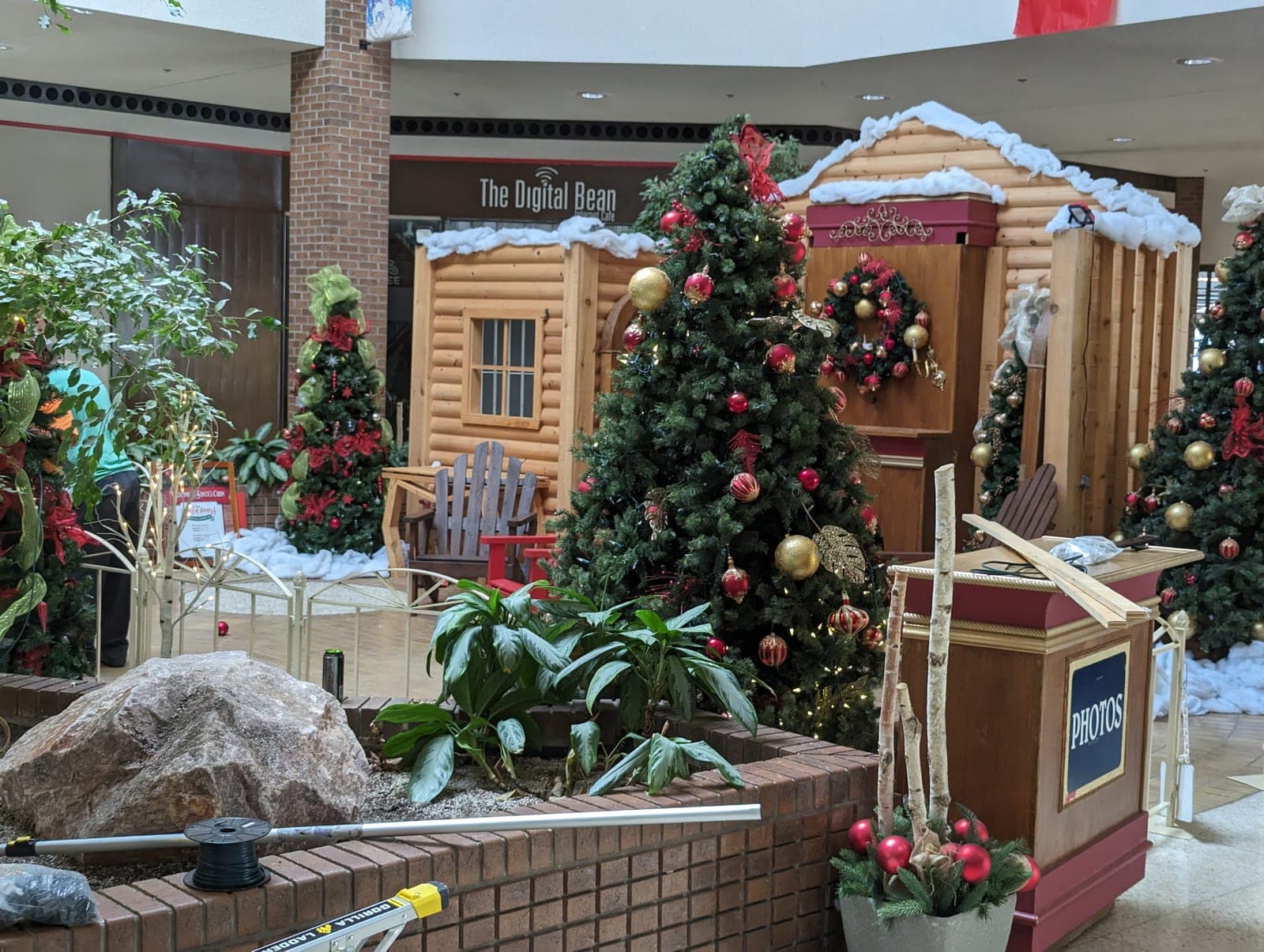 Shopping mall Santa's log cabin Christmas display with decorated trees and a photo podium
